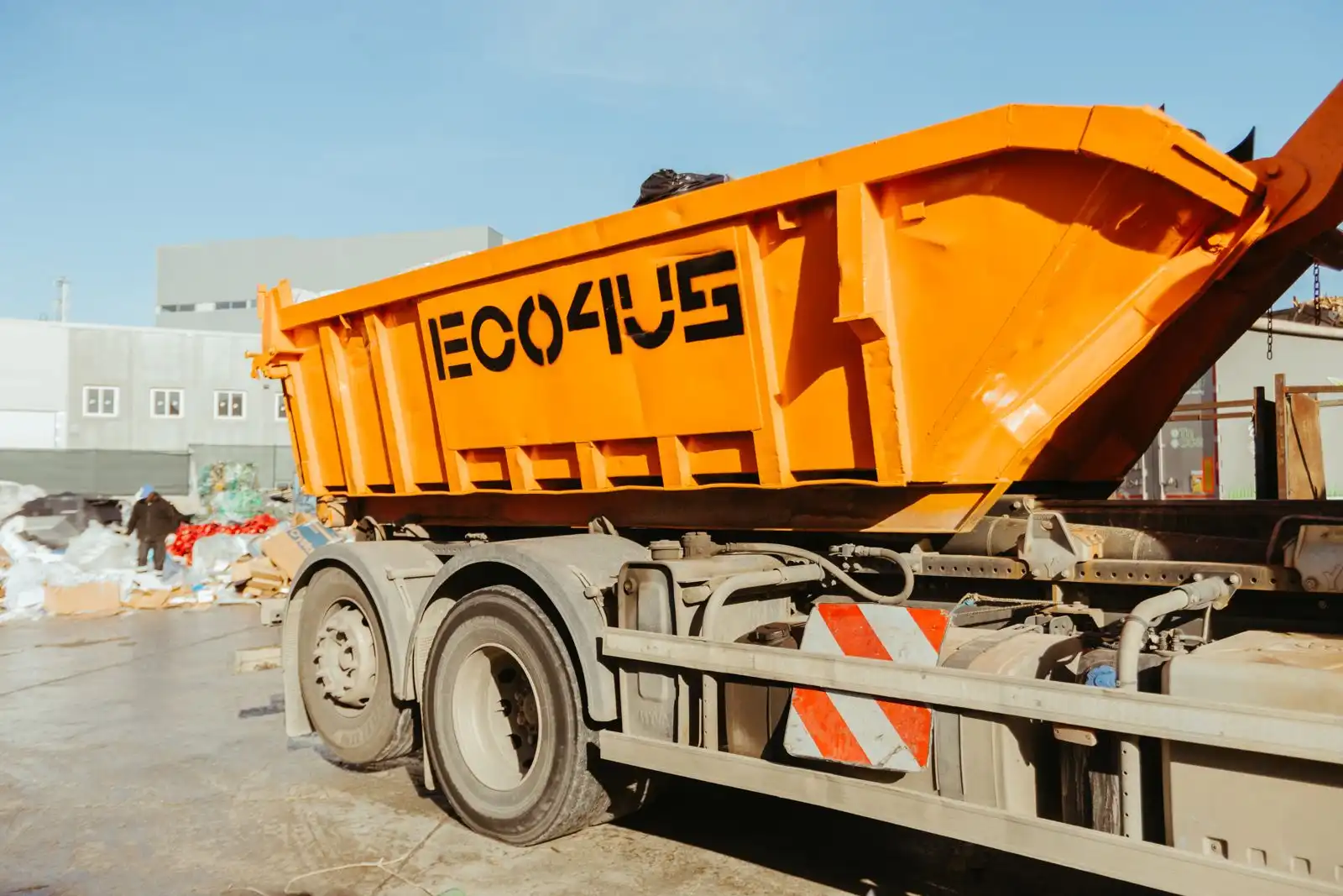 Contenedor naranja de ECO4US cargándose en un camión
