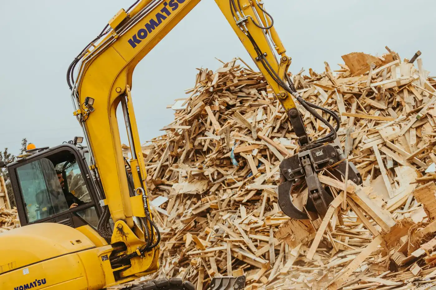Excavadora con pinza gestionando restos de madera para valorizar en ECO4US